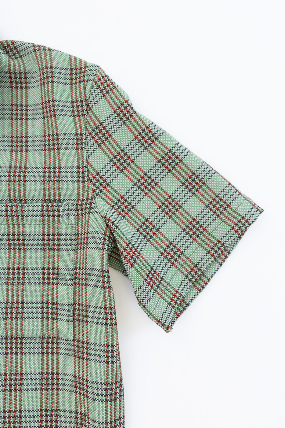 Close-up of short sleeve and shoulder, right side, green plaid lounge shirt fabric texture.