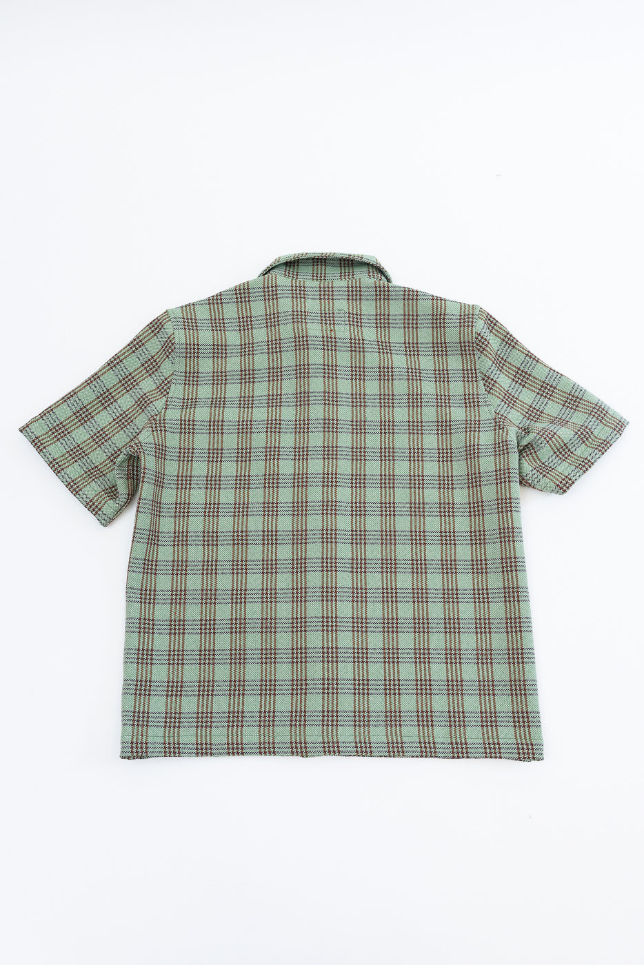 Flat lay of green plaid short sleeve lounge shirt, back view, showing collar and pattern detail.