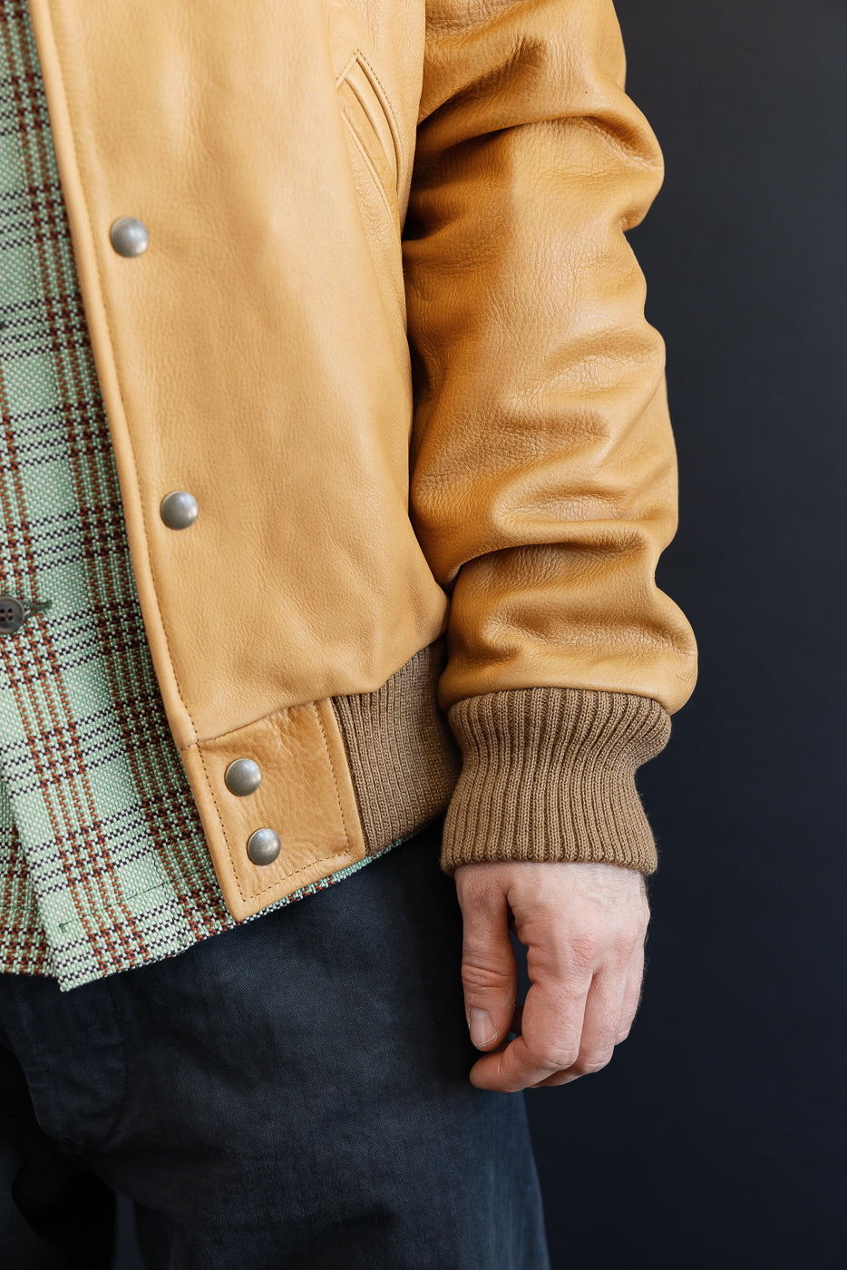 Close-up front left side of tan leather jacket on male model, 5'9
