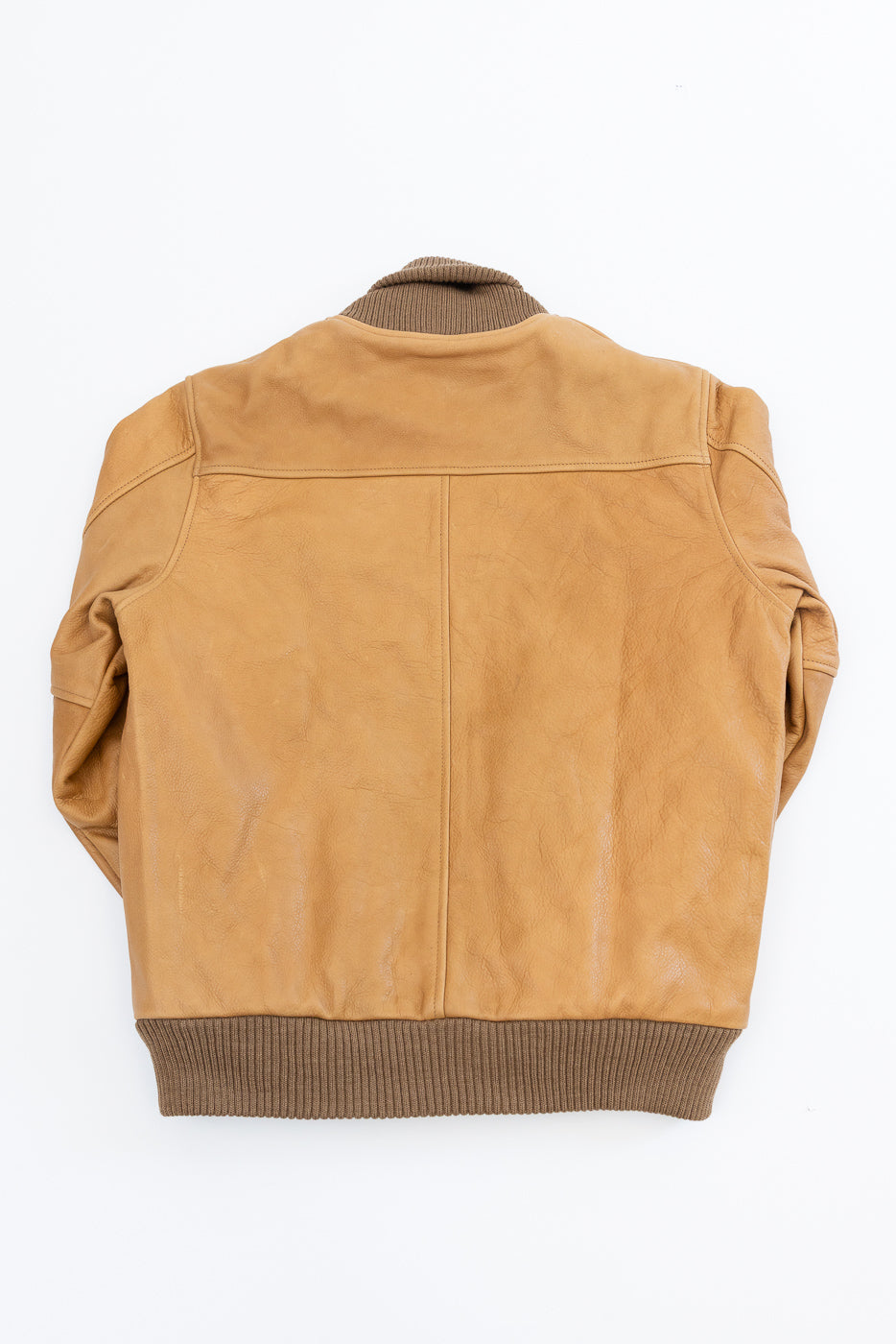 Flat lay of rust tan leather jacket back, showing ribbed collar and hem, no model present.