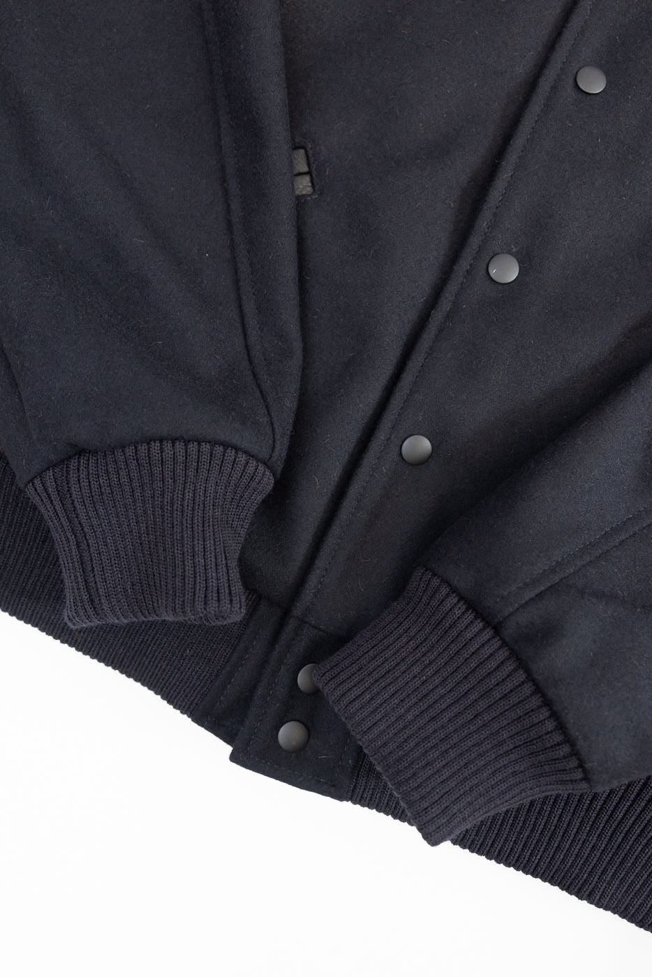 close up of ribbed sleeve cuffs and hem with matte black buttons on placket