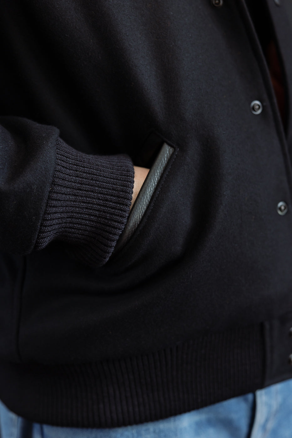 close up of leather welted pocket with ribbed sleeve showing hand in pocket