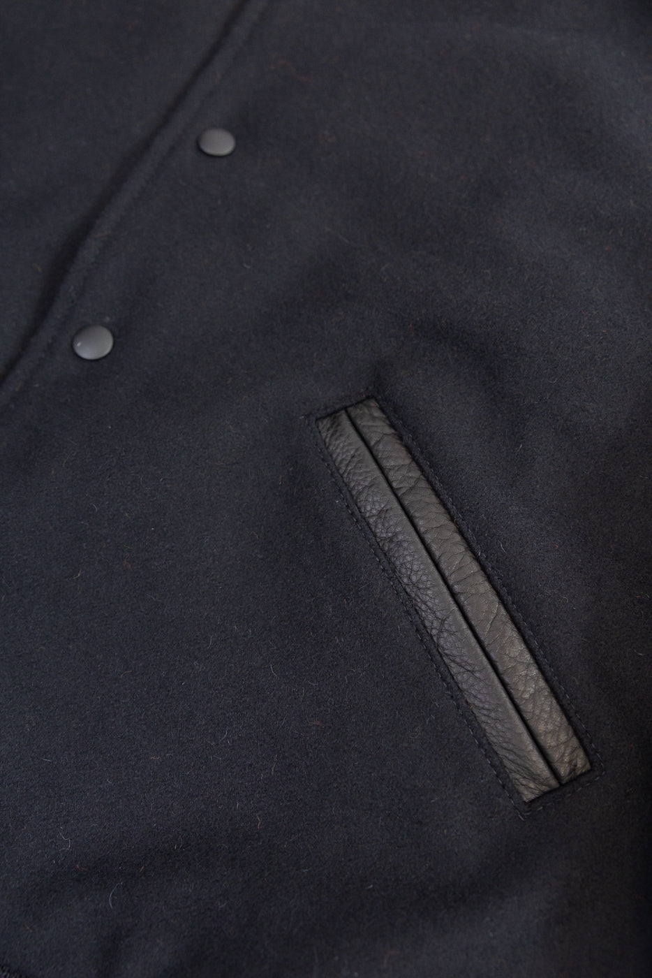 close up of black leather welt hand warmer pocket