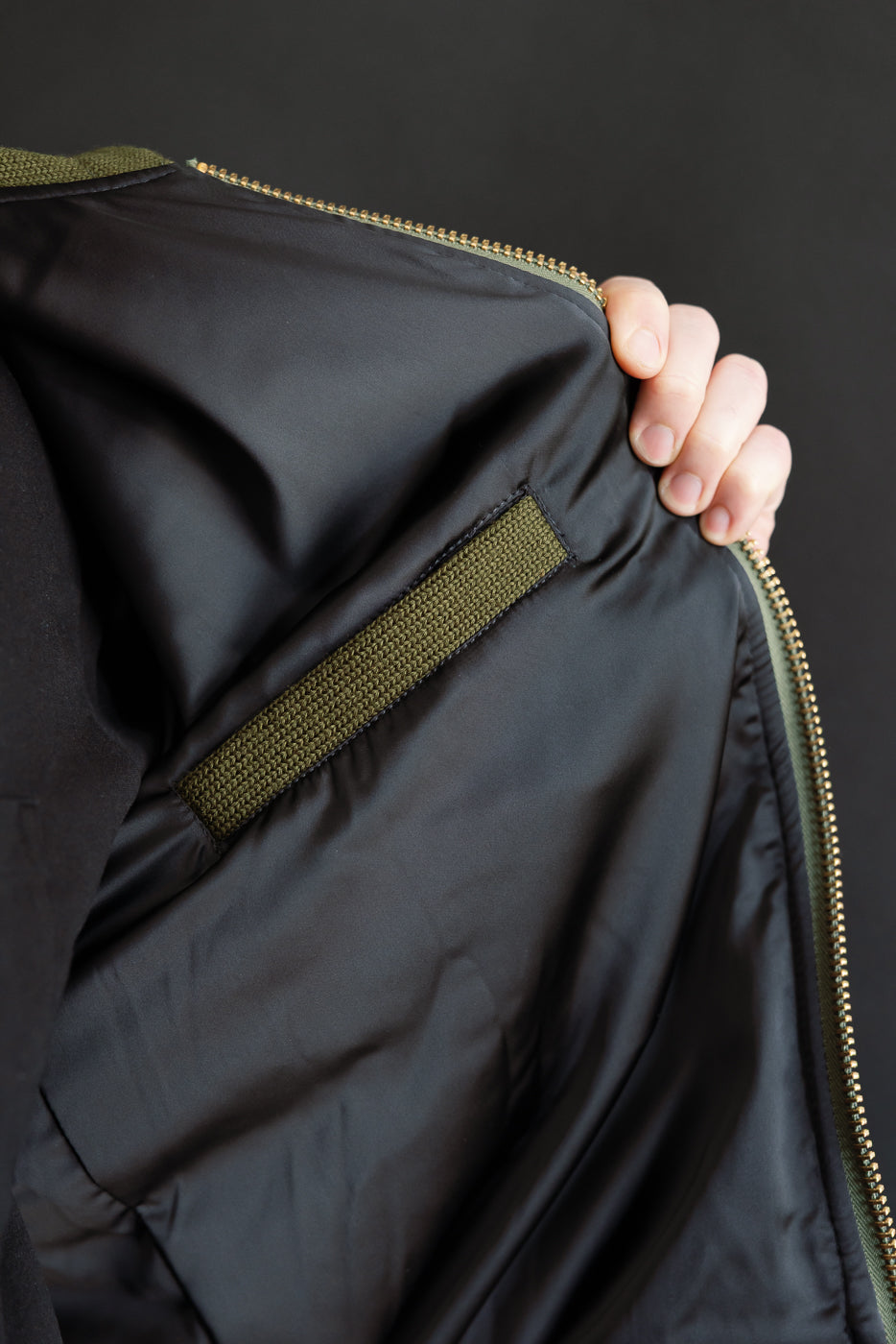 close up of black satin interior with a olive green welted interior pocket