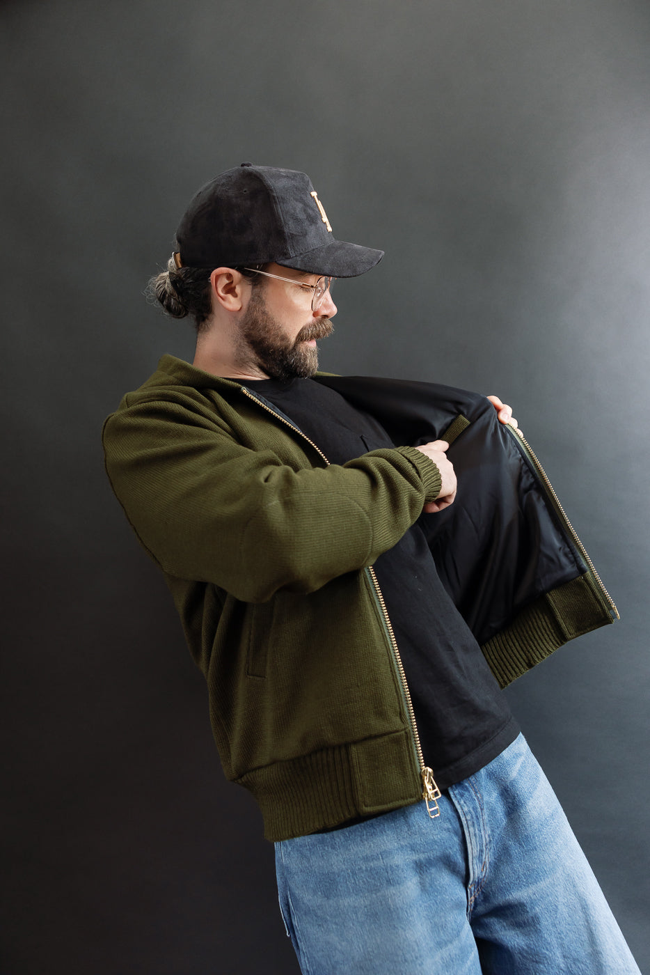 angles shot of man wearing the olive green hoodie and opening the front to show the interior pocket in black satin liner