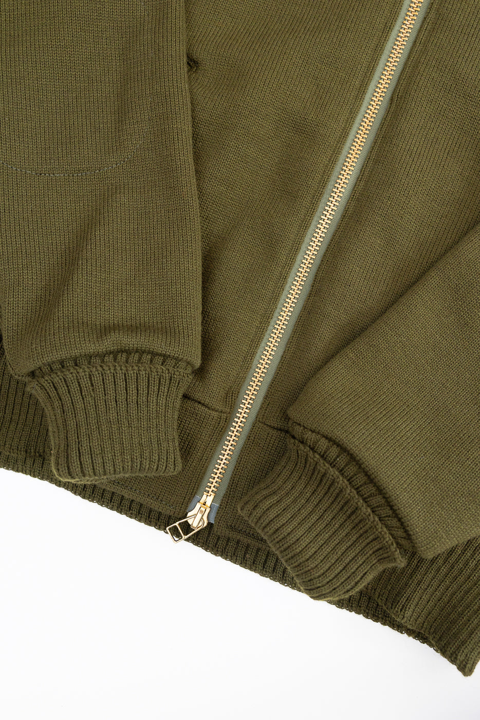 close up of brass zipper and hem on knitted olive green zip up hoodie