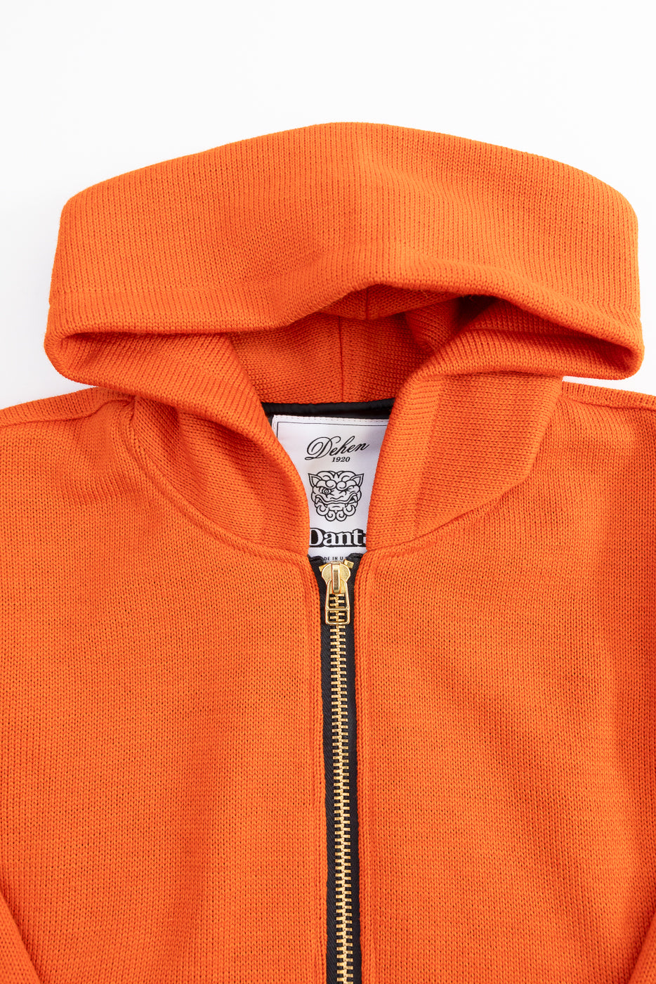 close up of brass zipper on orange knitted hoodie