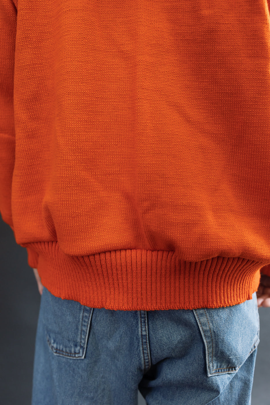 close up of orange knitted hoodie, back hem
