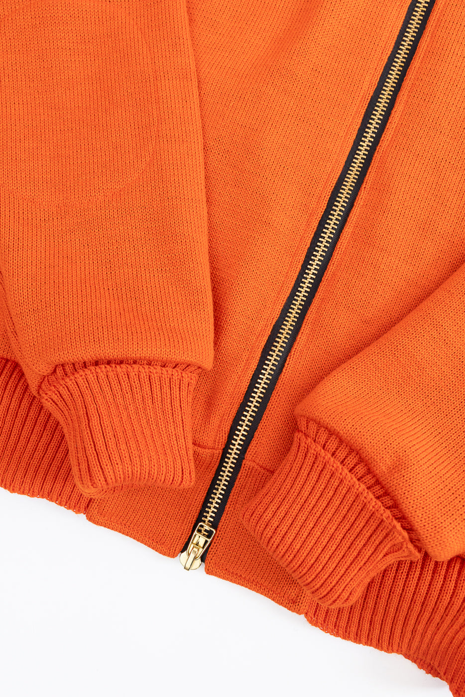 Close-up of an orange jacket with a gold zipper on a white background