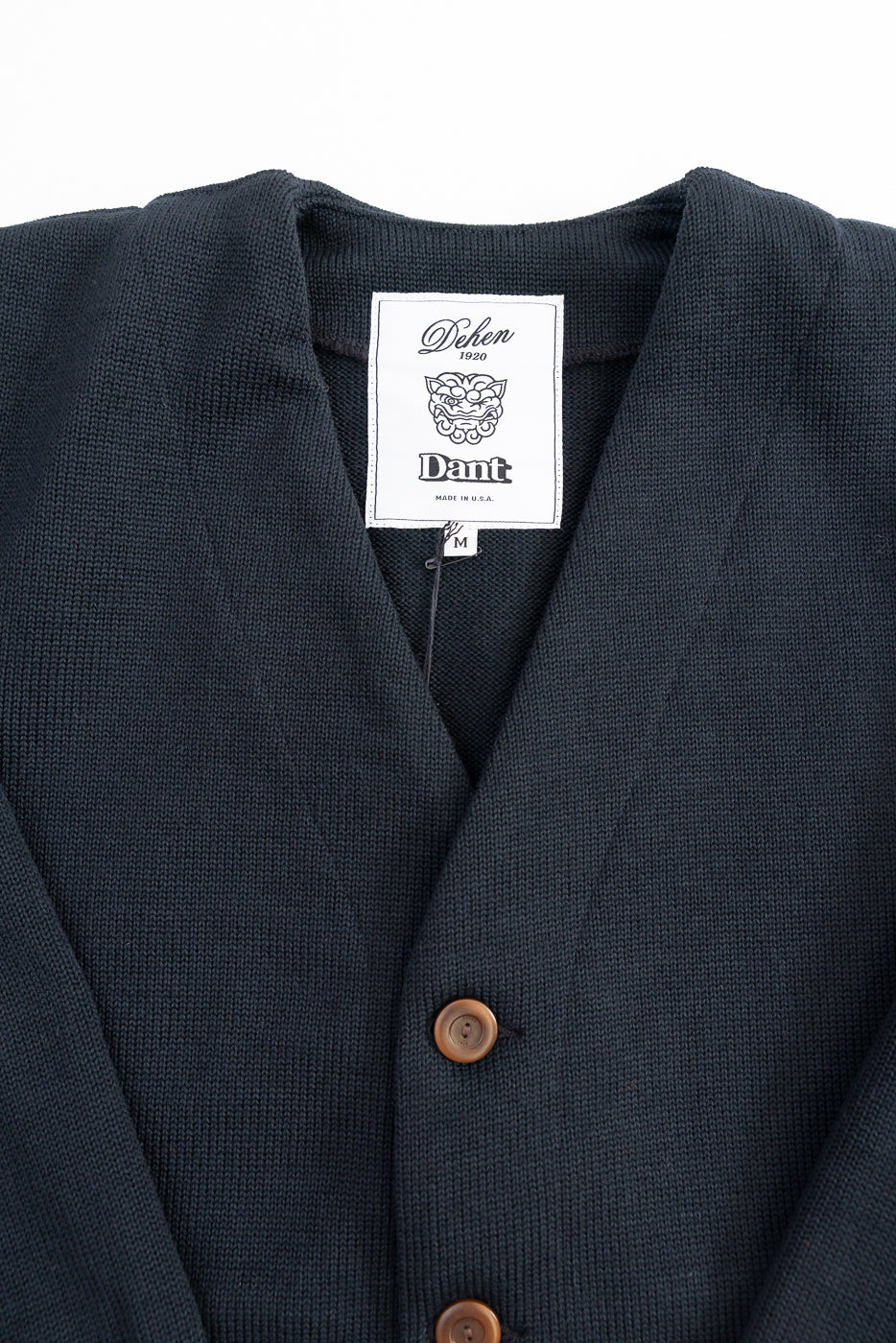 Black Dant slouchy cardigan with brown buttons on a white background, logo close up at nape