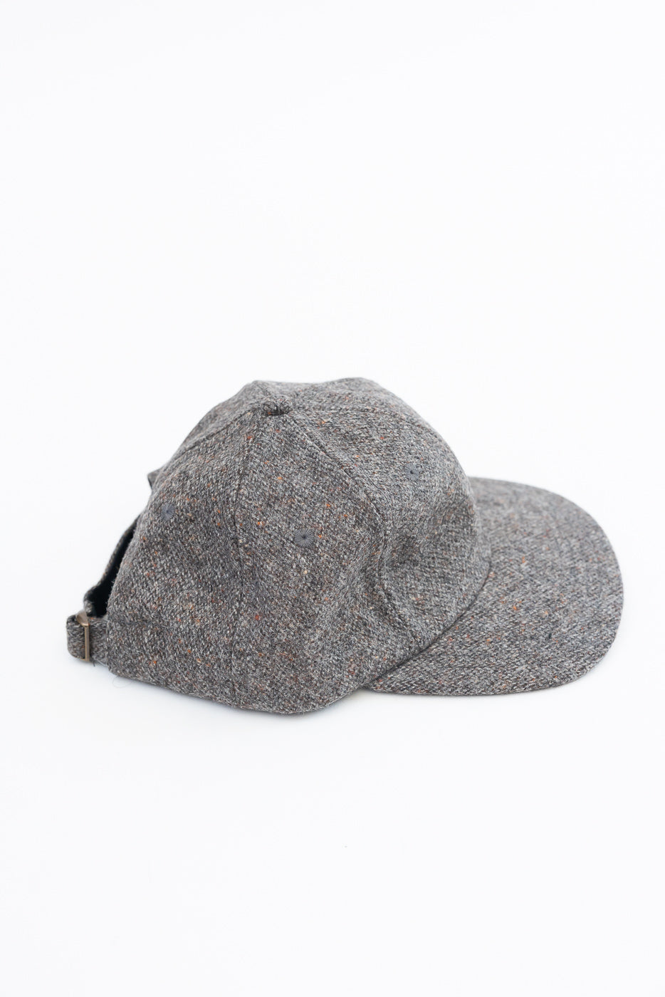 Close-up side view of a grey textured fabric baseball cap showing the back strap and brim.