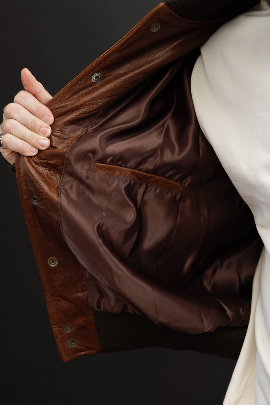 Close-up showing the brown leather interior and lining of a male model's jacket.