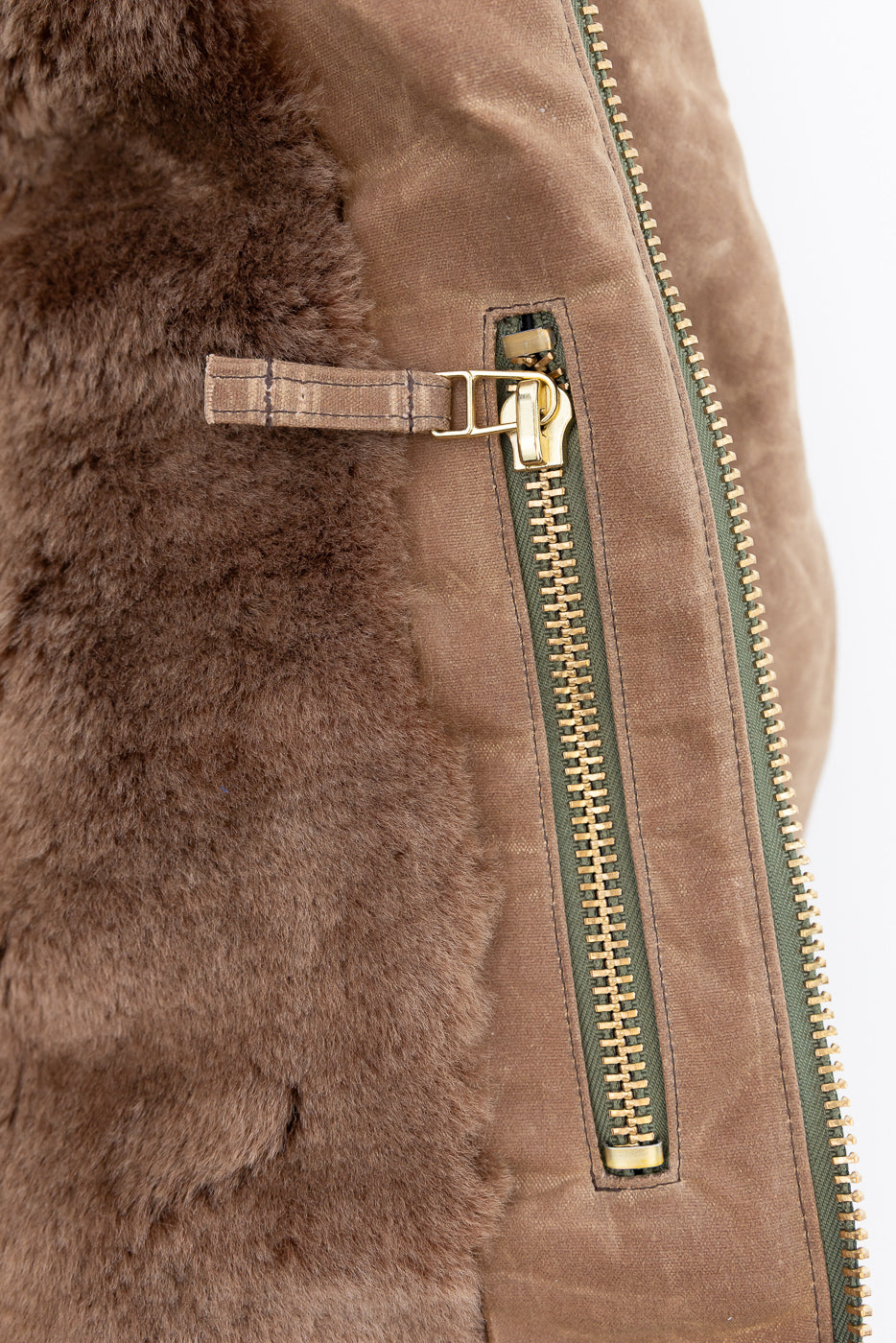 Close-up of the side zipper and brown shearling texture on a tan jacket.