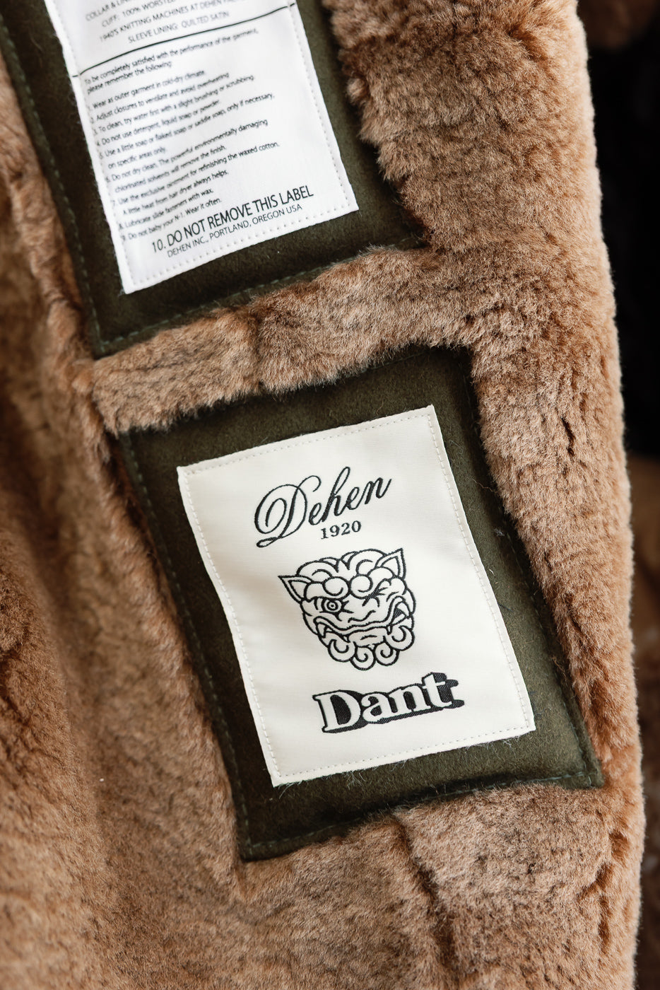 Close-up of inner lining and Dehen and Dant brand tags on a brown faux fur garment.