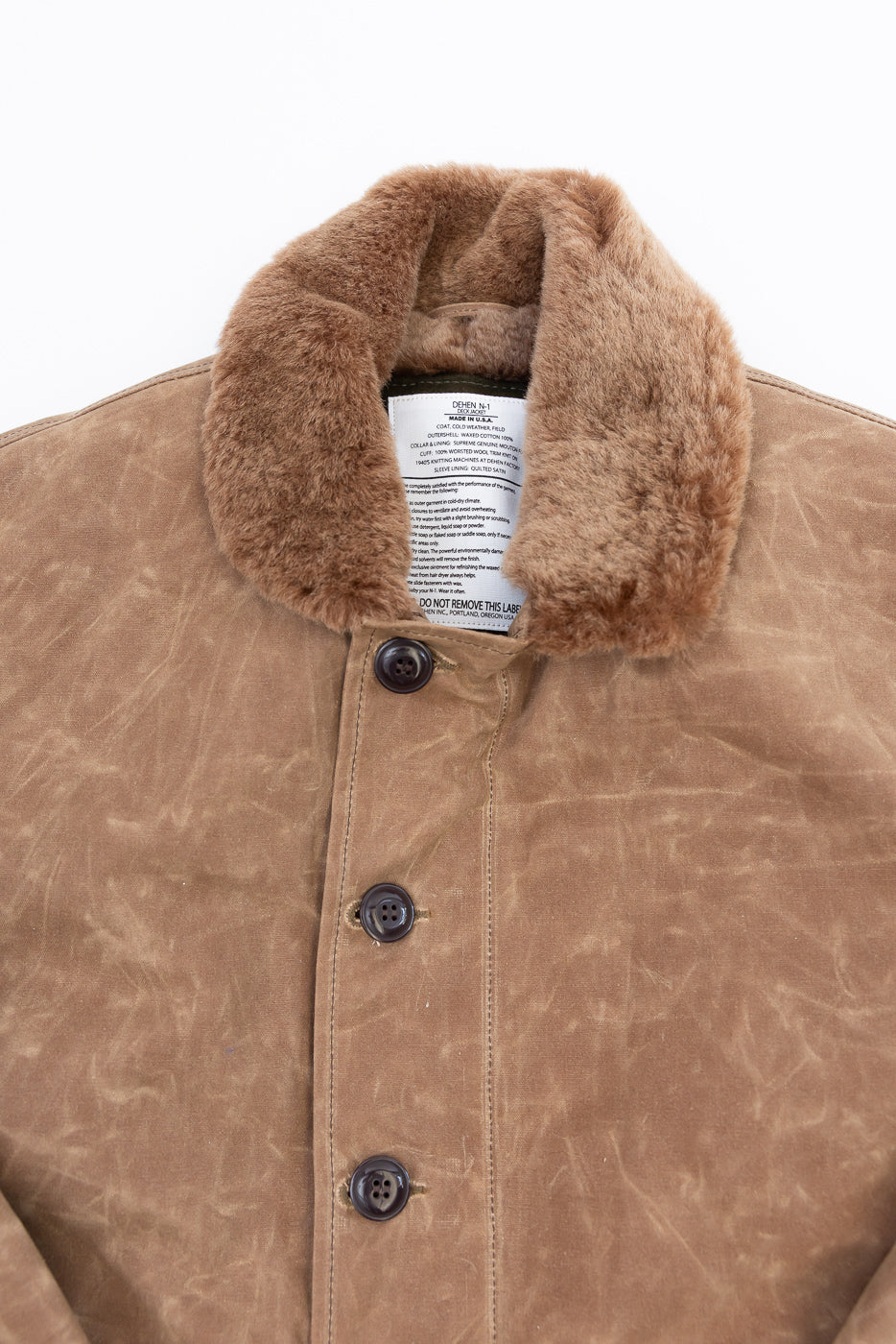 Close-up front view of a tan canvas jacket showing the faux-fur collar and button details.