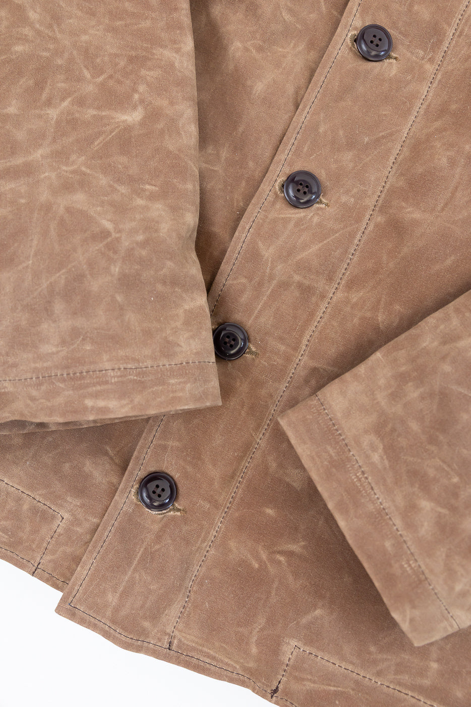 Close-up front view of a brown waxed canvas jacket showing button details and fabric texture.