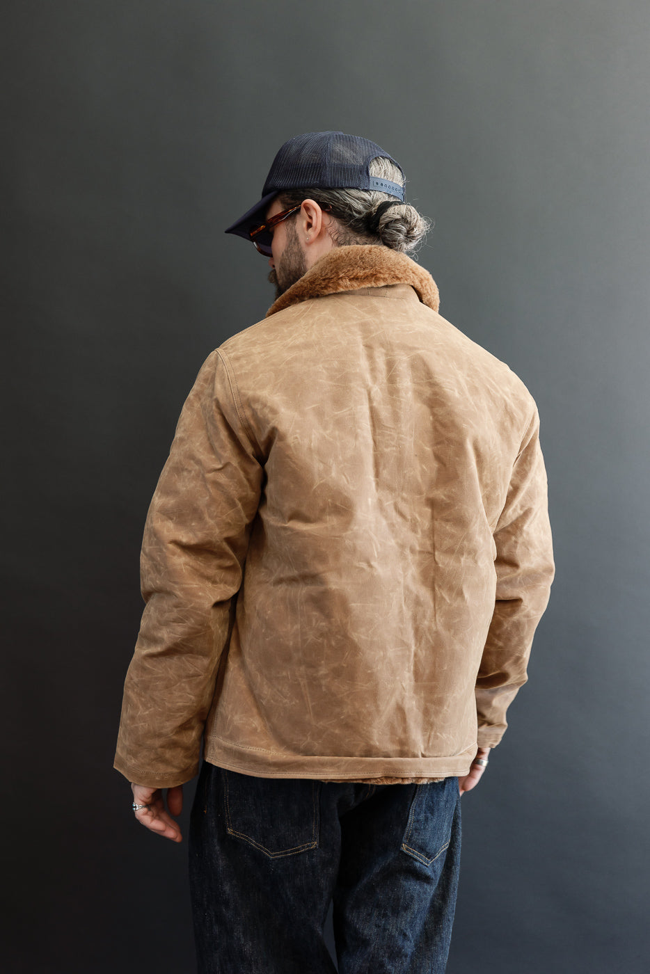 Back view of a tan faux-shearling collar jacket on a 5'9