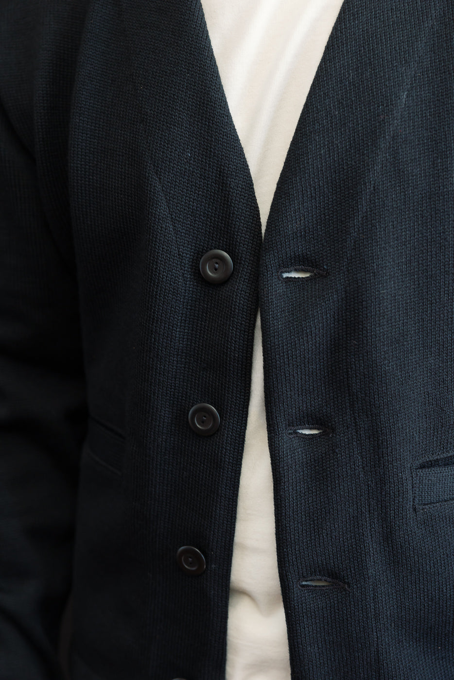 Close-up front view of navy knit blazer texture and dark buttons.