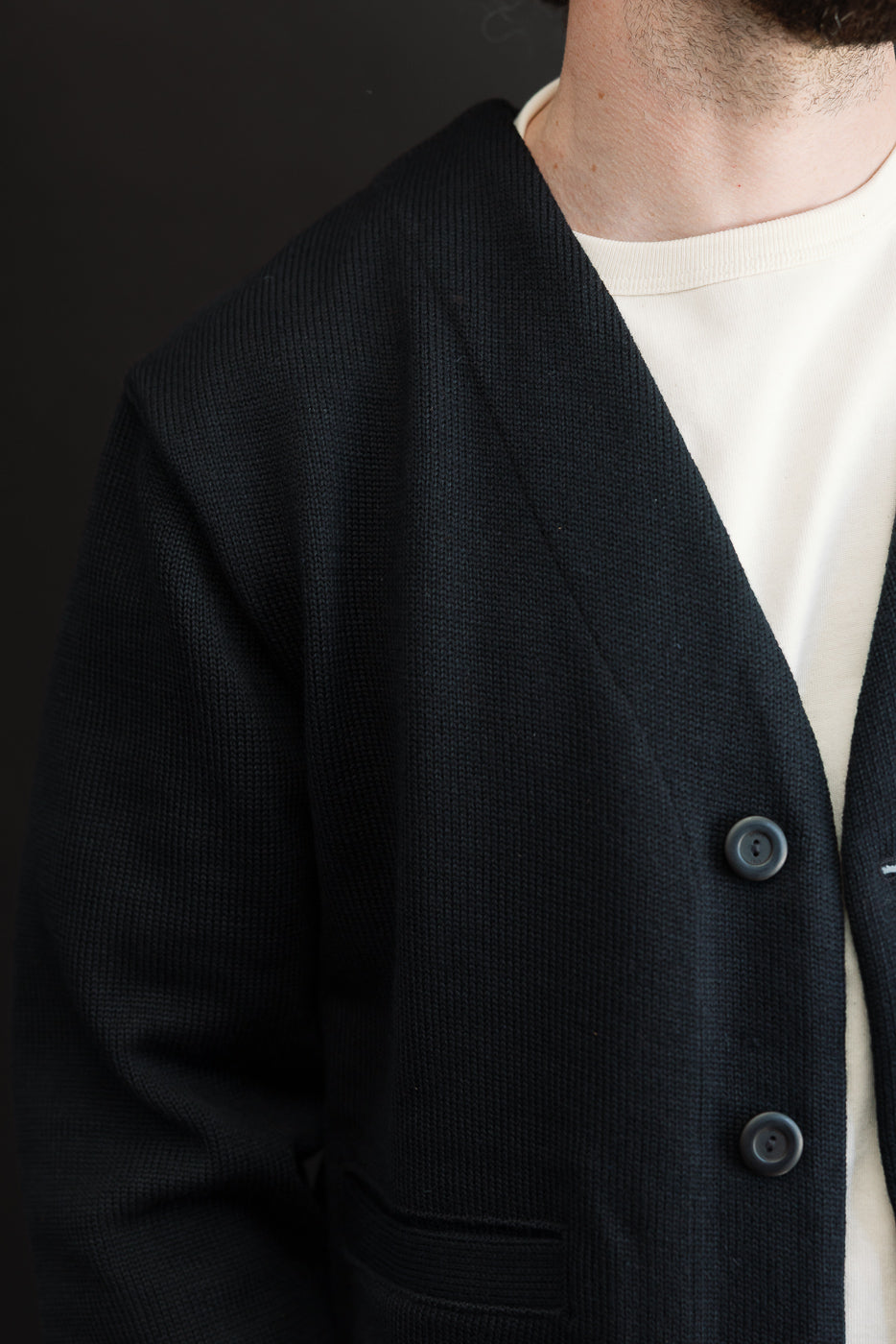 Close-up, side view of a black textured knit cardigan worn by a male model, 5'9