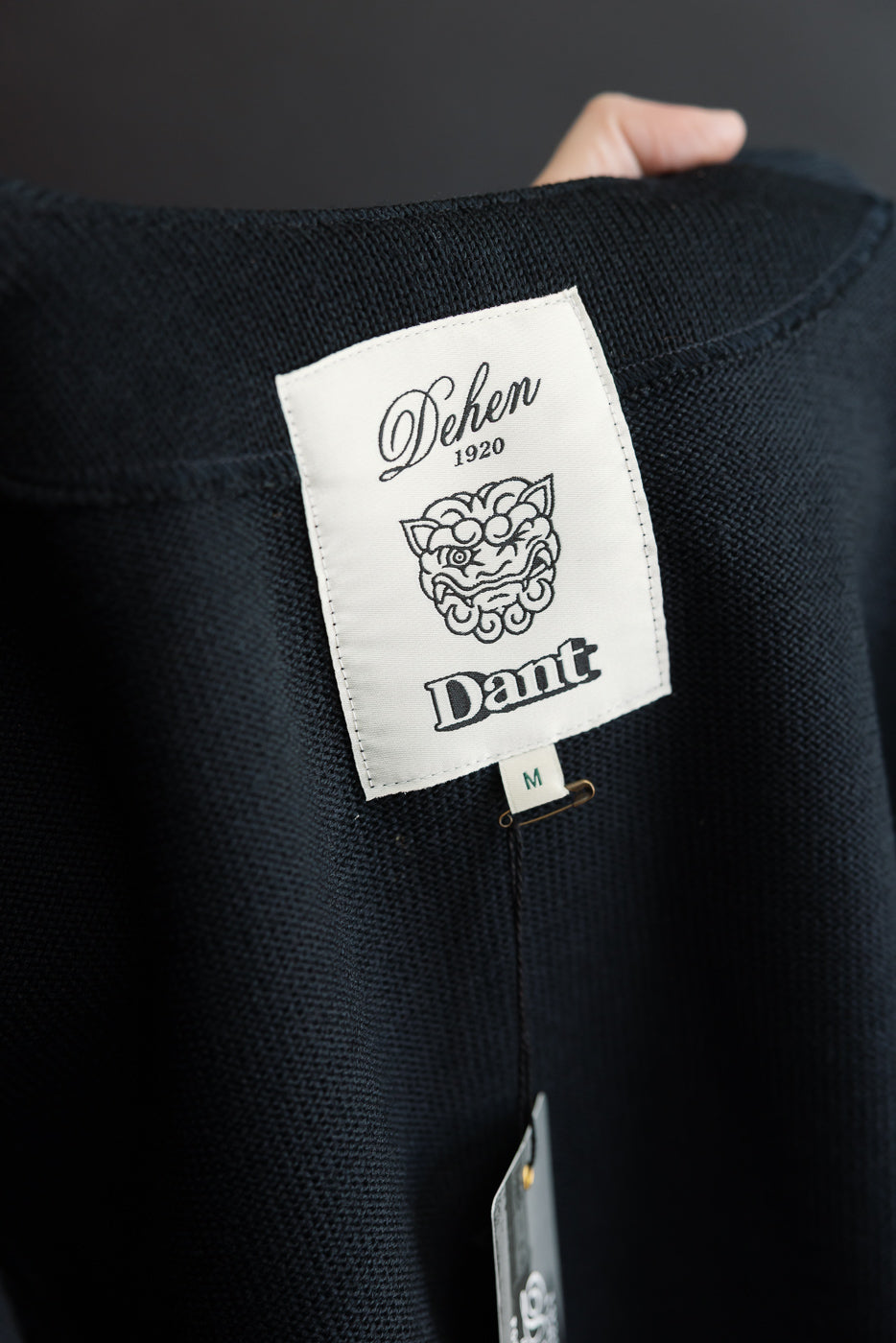 Close-up of the back neck area showing the white Dehen 1920 and Dant brand label on navy knit fabric.