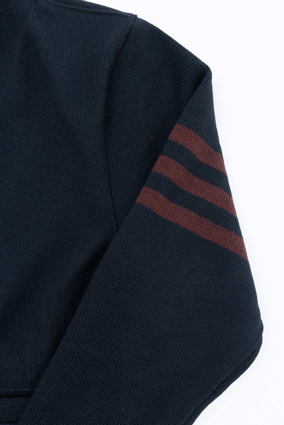 Close-up of the left sleeve of a navy blue knit sweater featuring brown striped details.