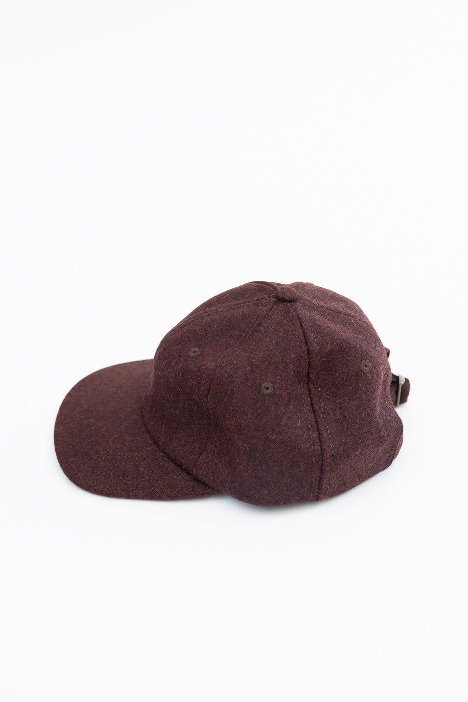 Close-up side view of a dark brown wool felt baseball cap showing the texture and side strap.