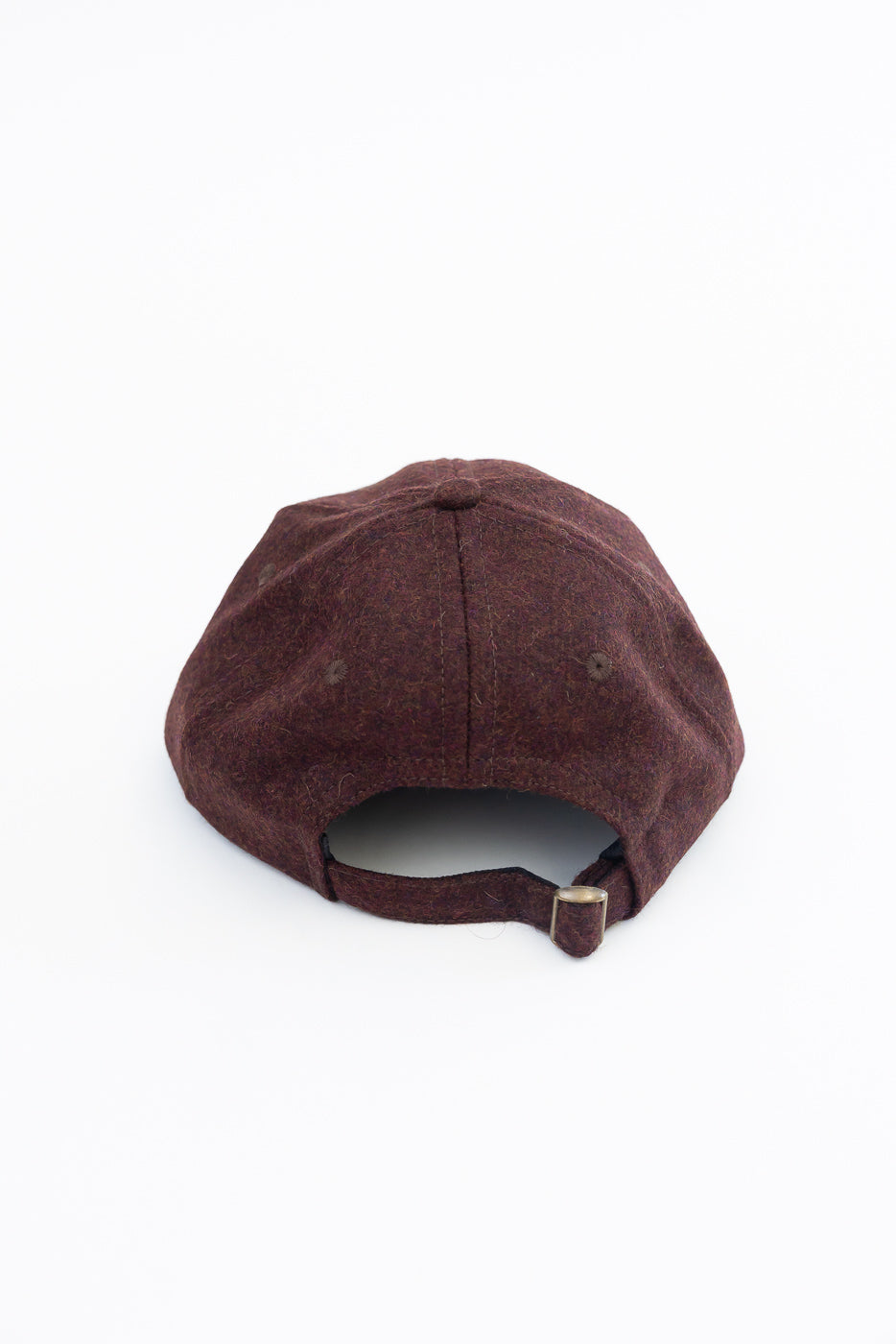 Back view close-up of a burgundy textured wool baseball cap with an adjustable strap.