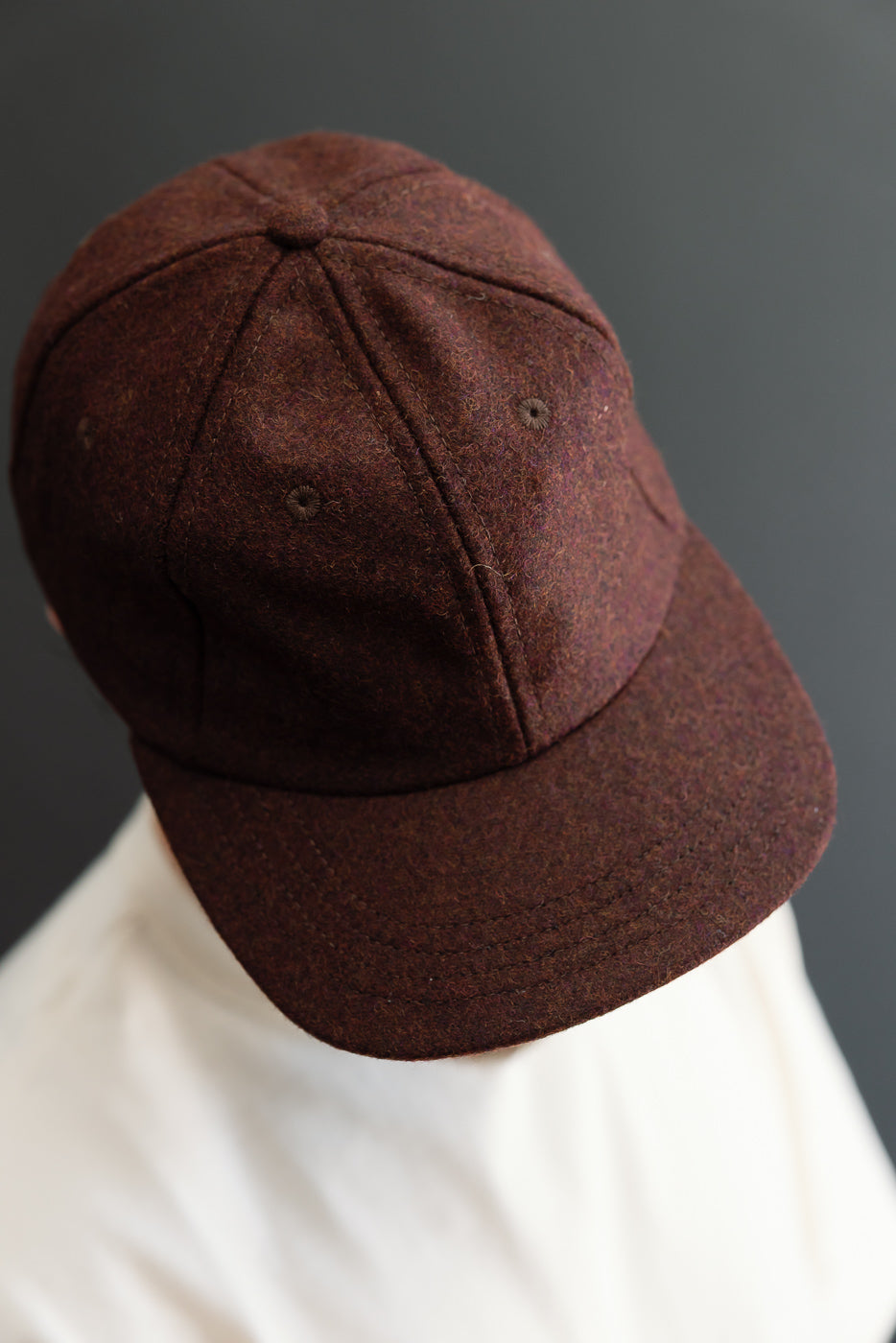 Close-up back view of a dark brown wool felt baseball cap showing textured fabric.