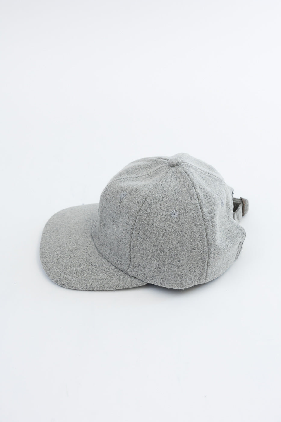 Side view close-up of a grey textured fabric baseball cap against a white background.