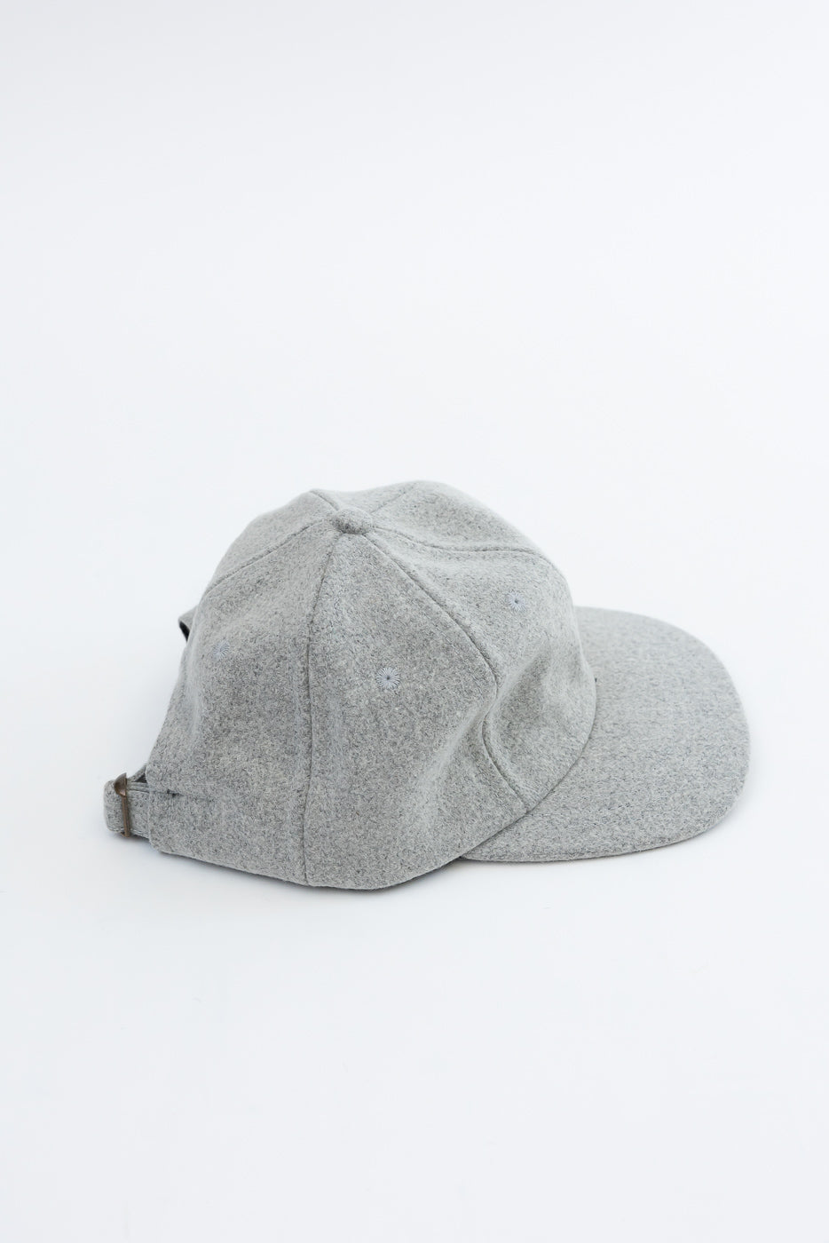 Side view flat lay of a grey textured fabric baseball cap on a white background.