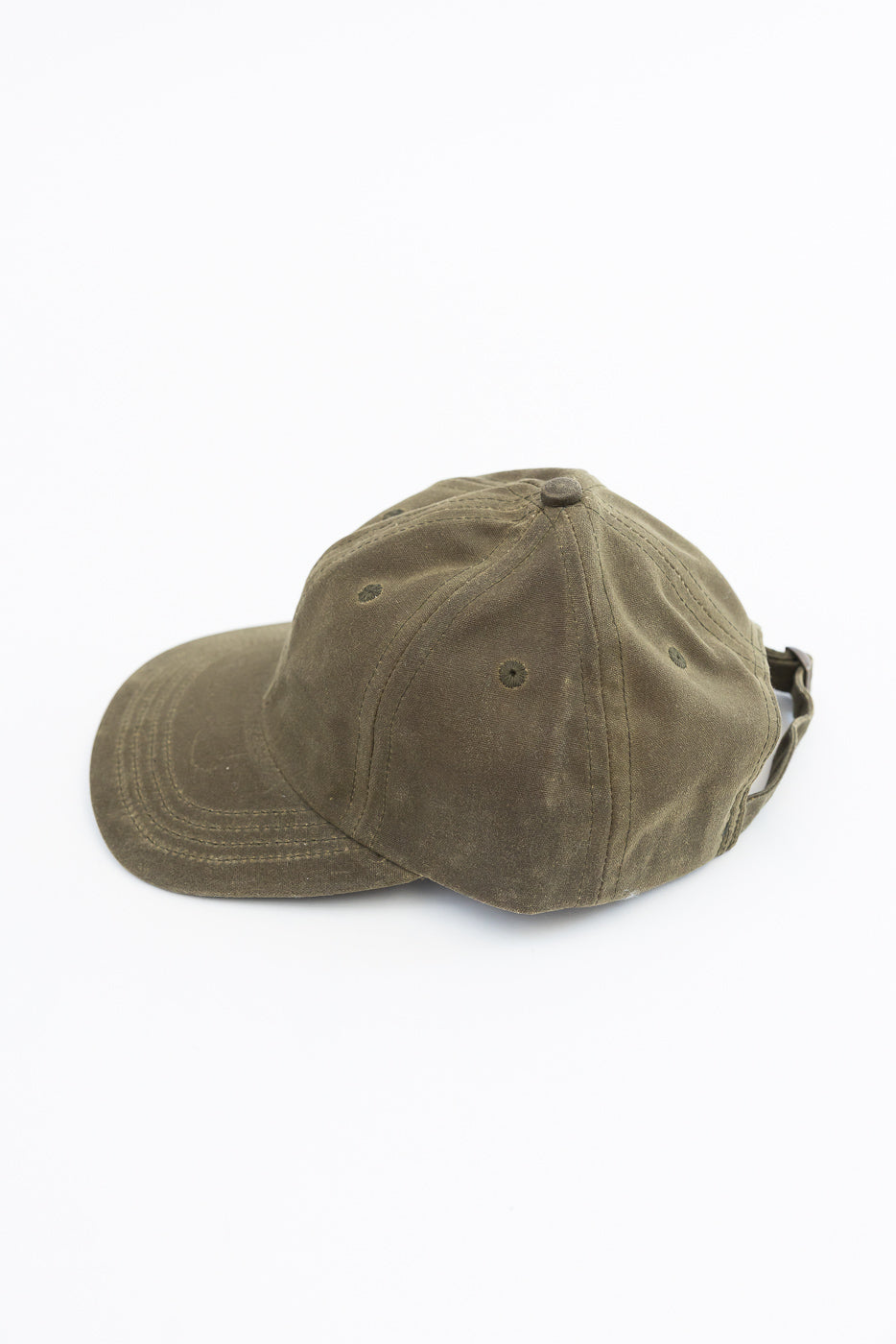 Close-up side view of an olive green cotton twill baseball cap on a white background.