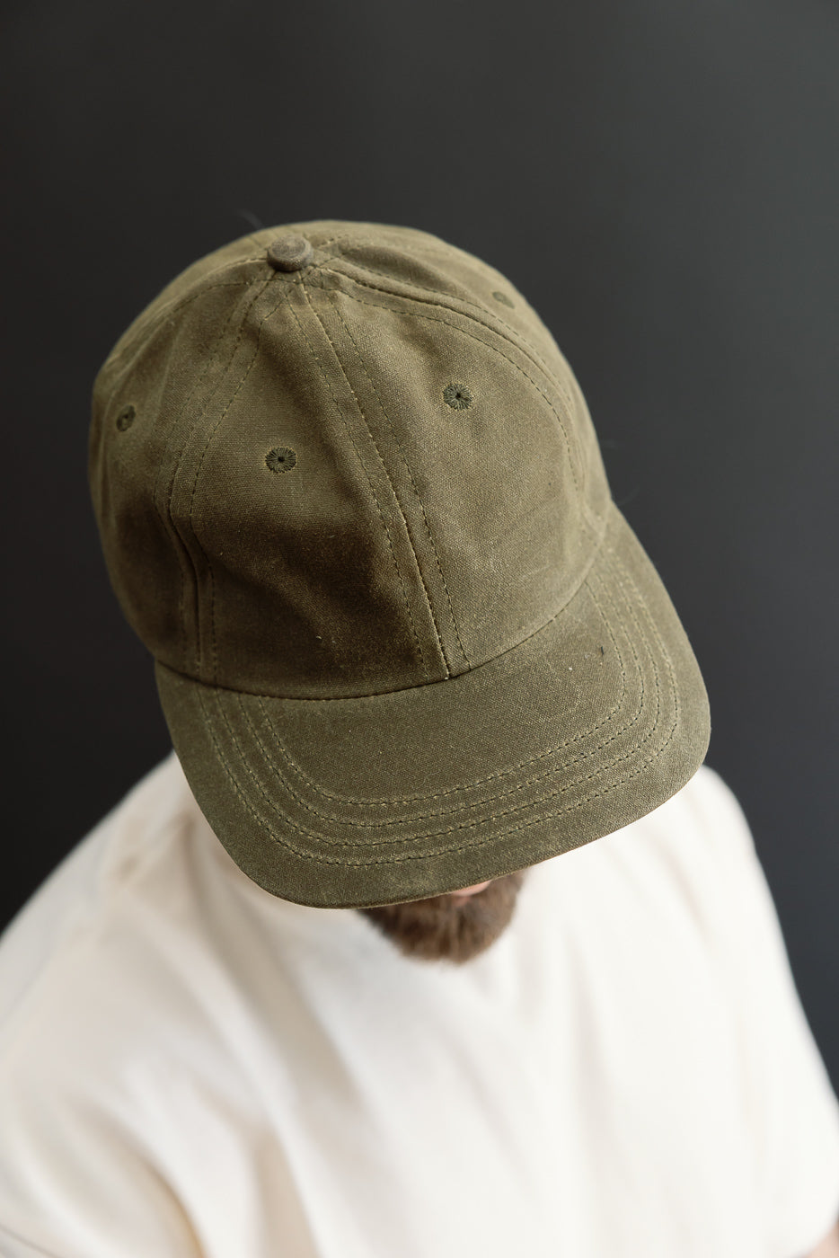 Close-up front view of an olive green canvas baseball cap on a male model.