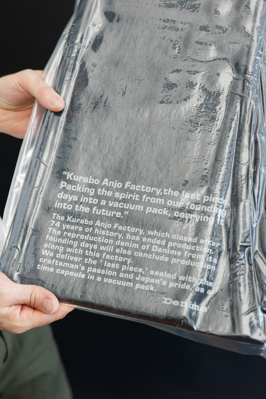 Close-up of the front of a vacuum-packed denim product in a clear plastic bag with printed text.
