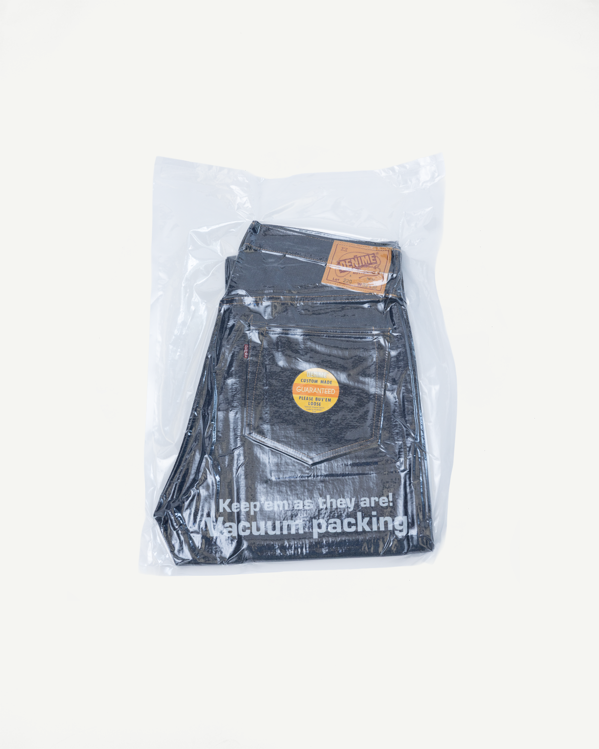 Flat lay back view of dark selvedge denim jeans in vacuum packaging.