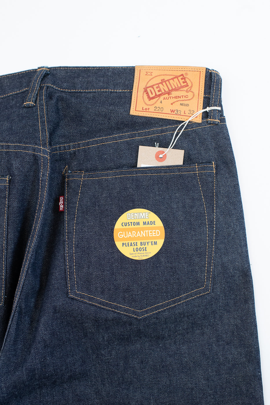 Blue denim jeans with a brand label and warranty tag on a white background