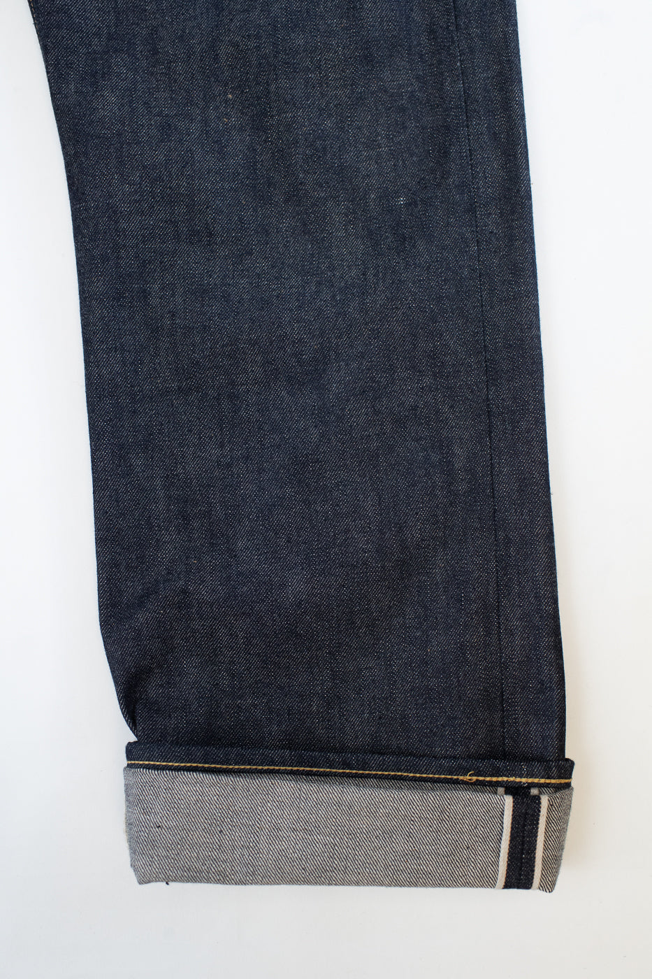 Dark blue jeans with a visible hem on a white background