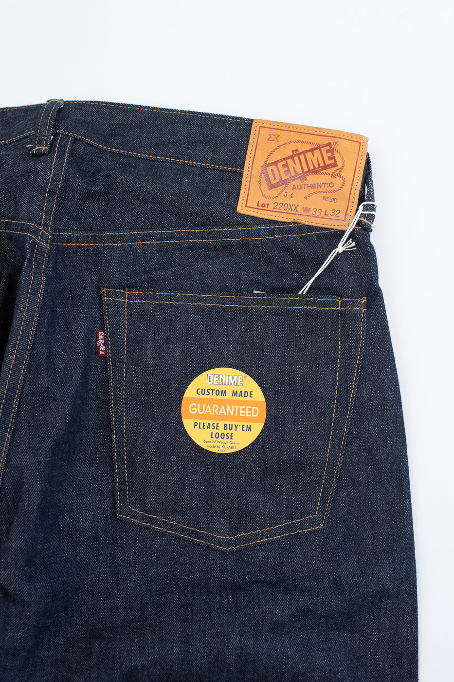 Dark blue denim jeans with a brand label on a white background