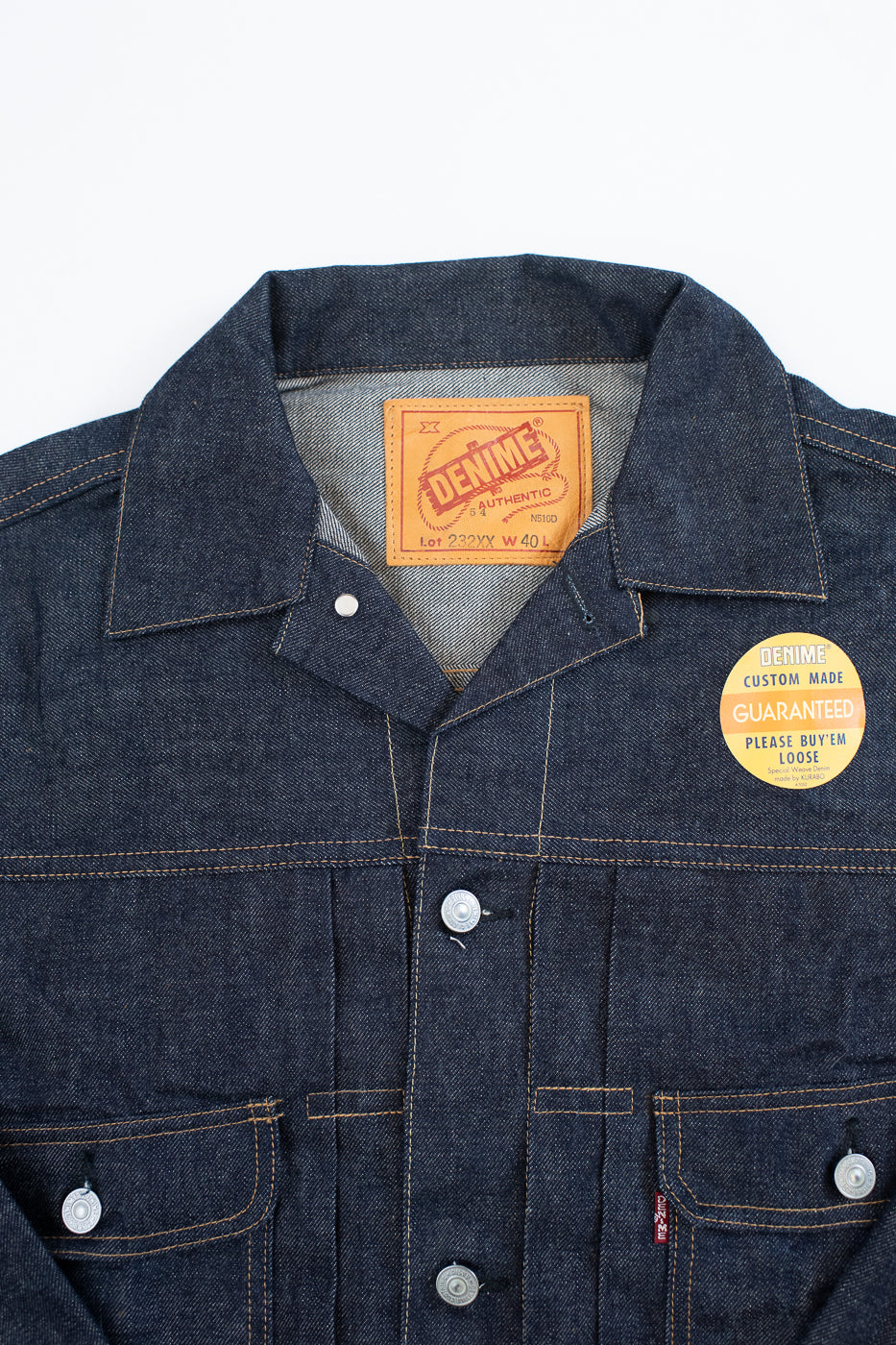 Denim jacket with brand label and custom made tag on a white background
