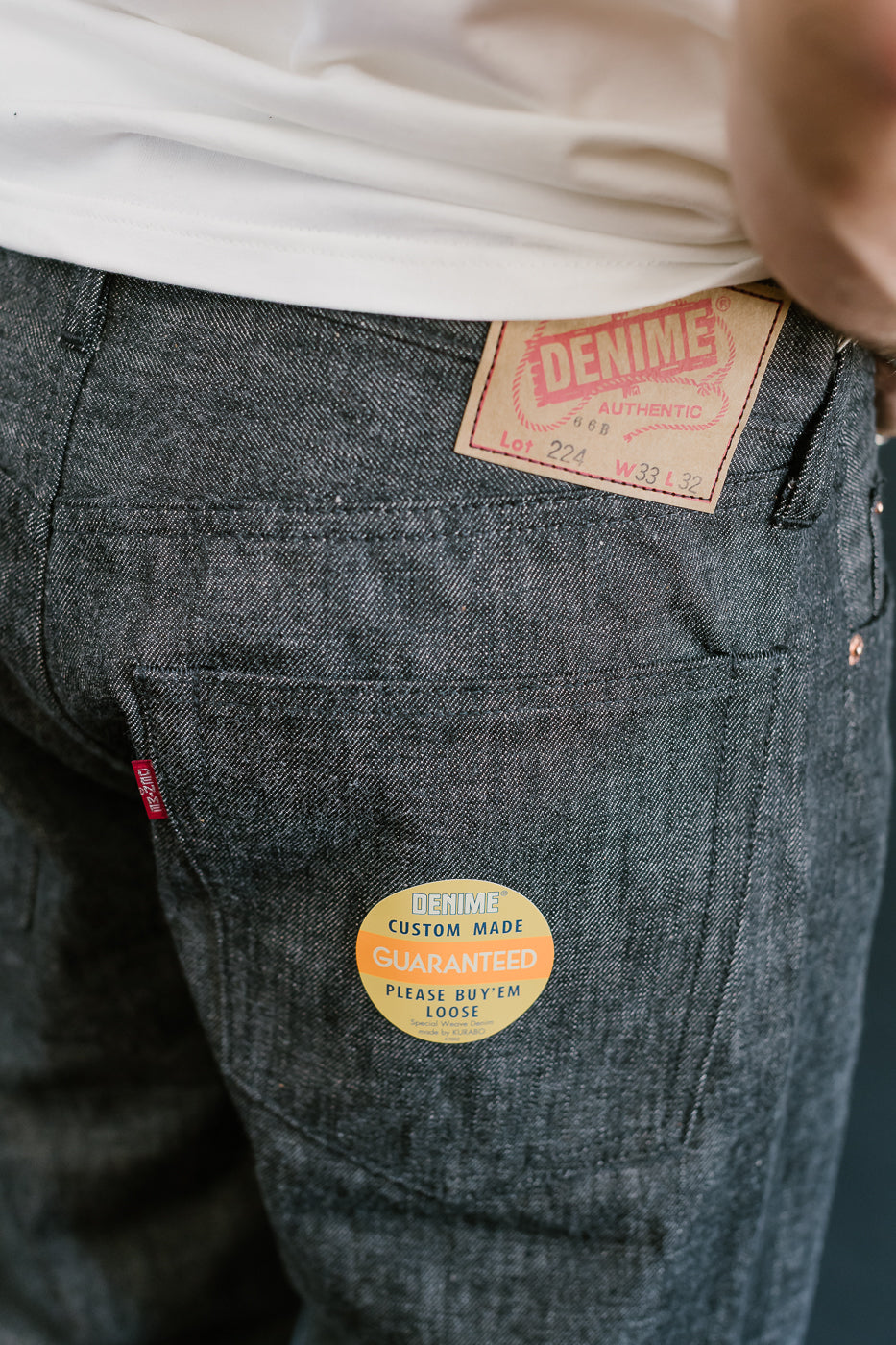 close up of on body denime black x mother cotton back pocket, paper patch, sticker and red tab