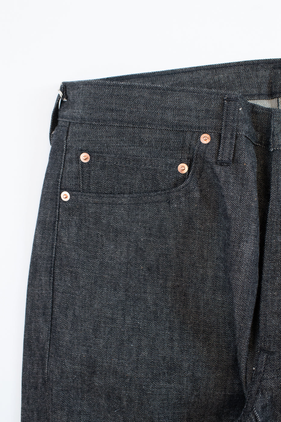 close up of coin pocket on black jeans on a white background