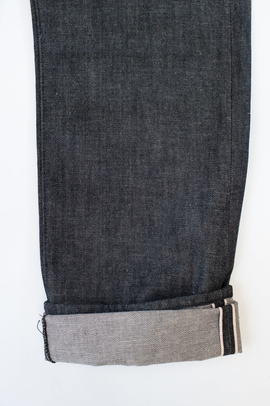 close up of cuff and selvedge id on black jeans on a white background