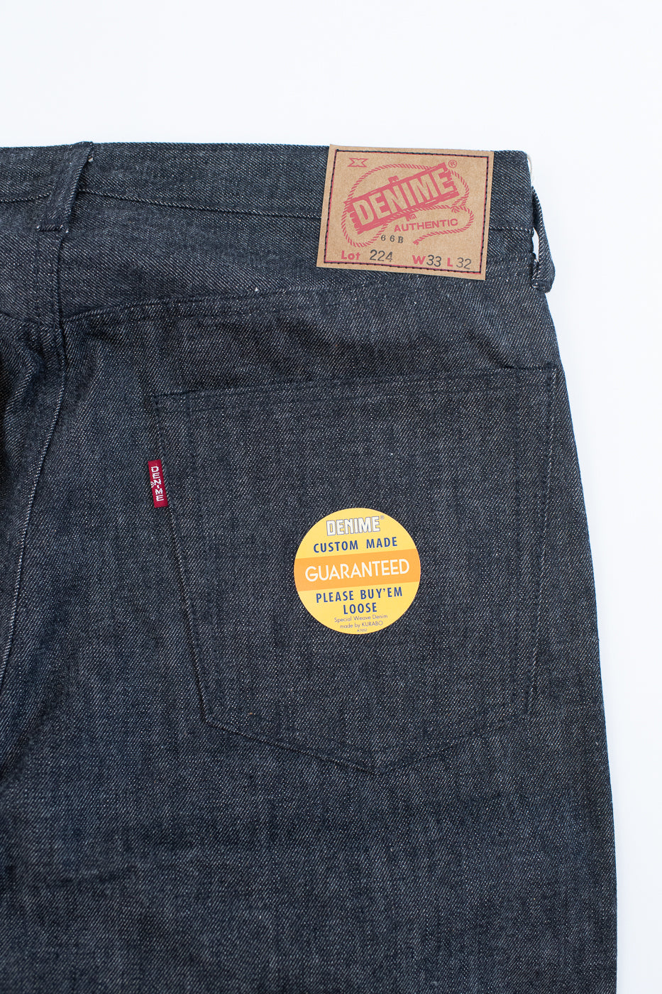 back pocket of black jeans on a white background. denime patch, sticker, and tab included
