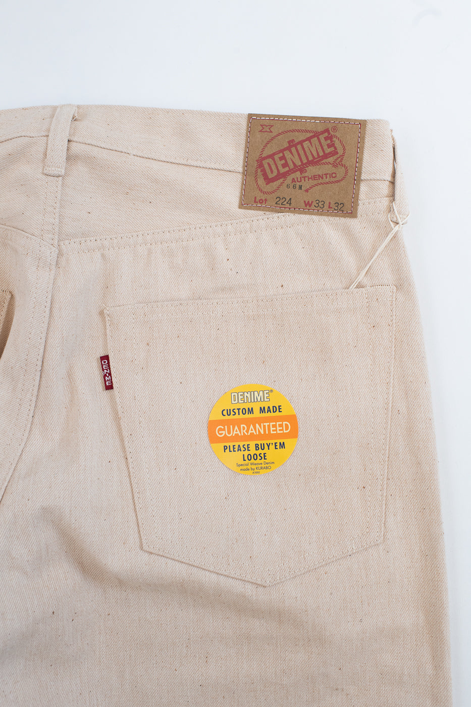 Beige pants with a brand label and sticker on a white background