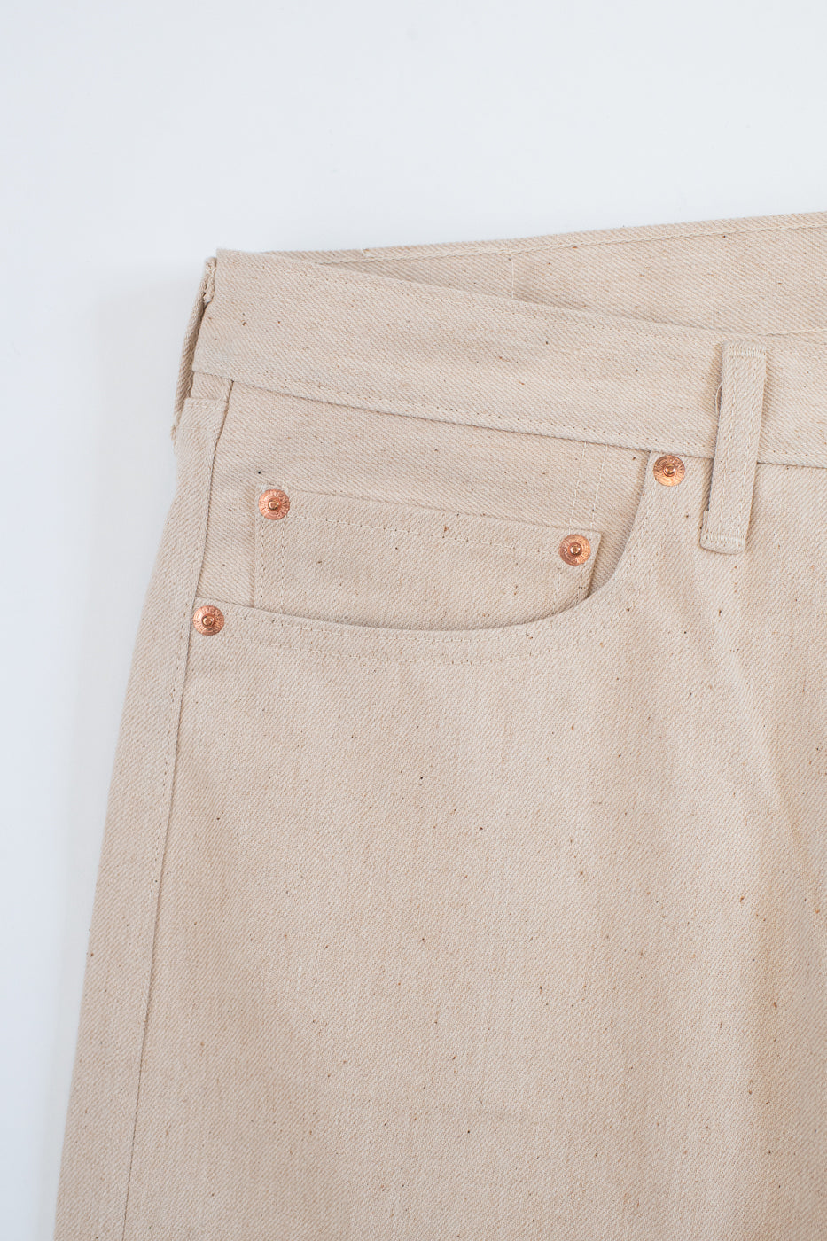 Close-up of beige pants with button details on a light gray background