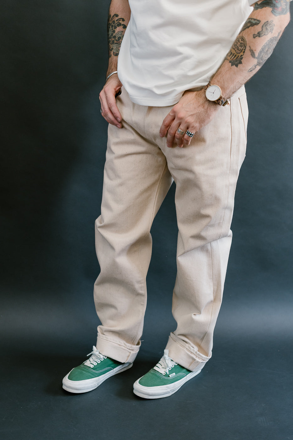 Person wearing beige pants and green sneakers on a dark background
