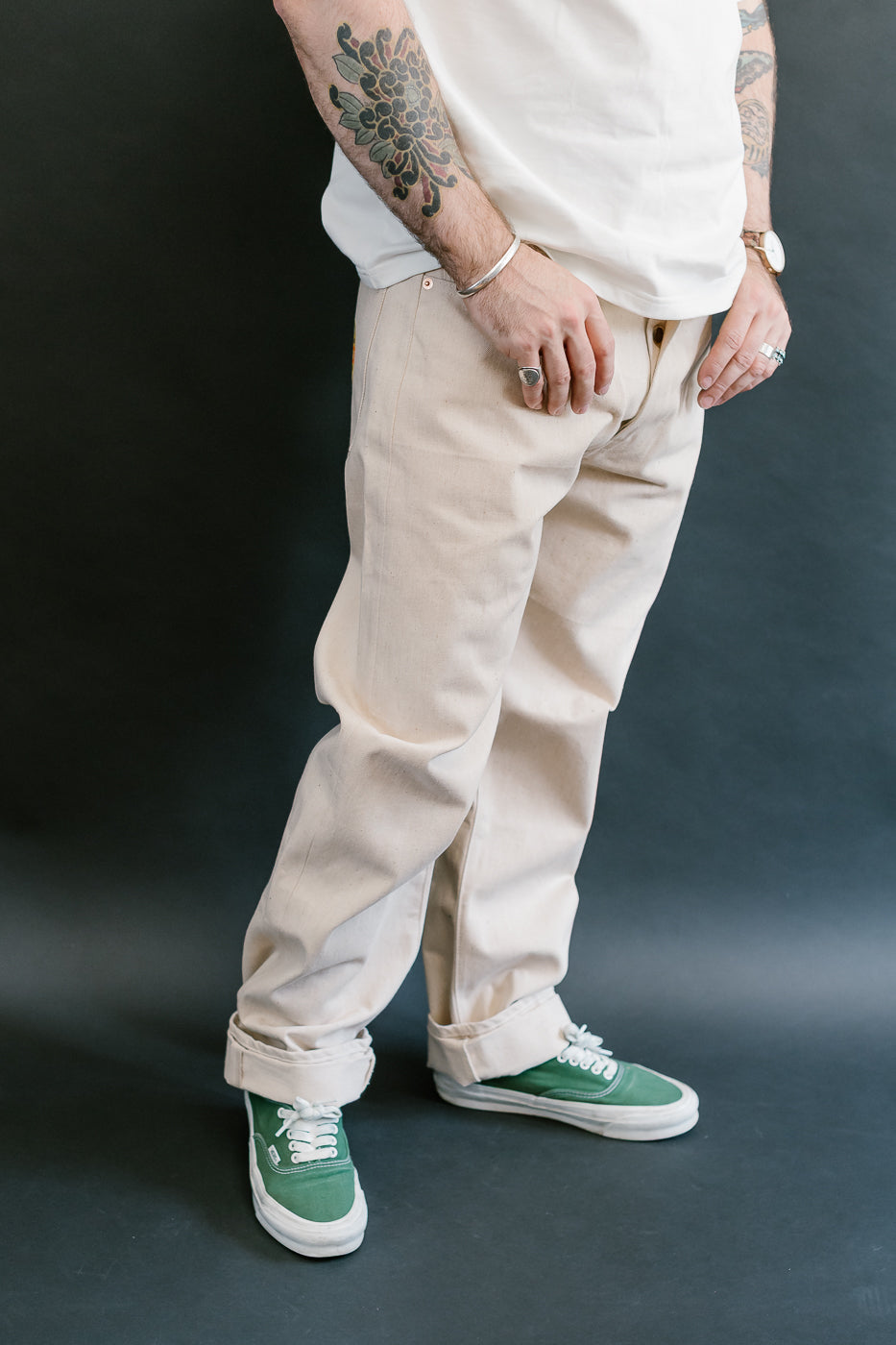 Person wearing beige pants and green sneakers on a dark background