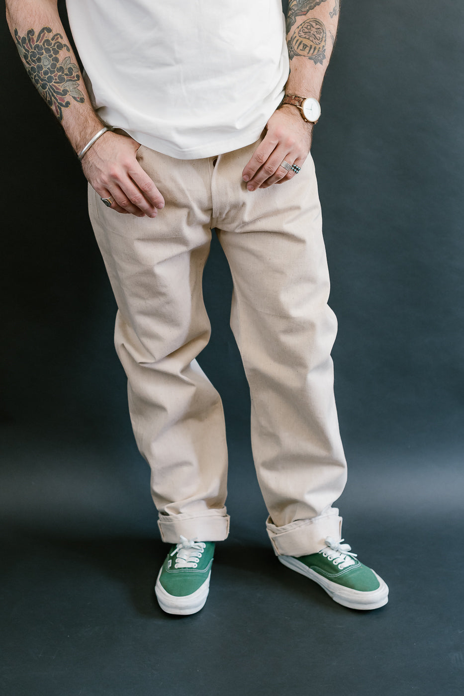 Person wearing beige pants and green sneakers on a dark background
