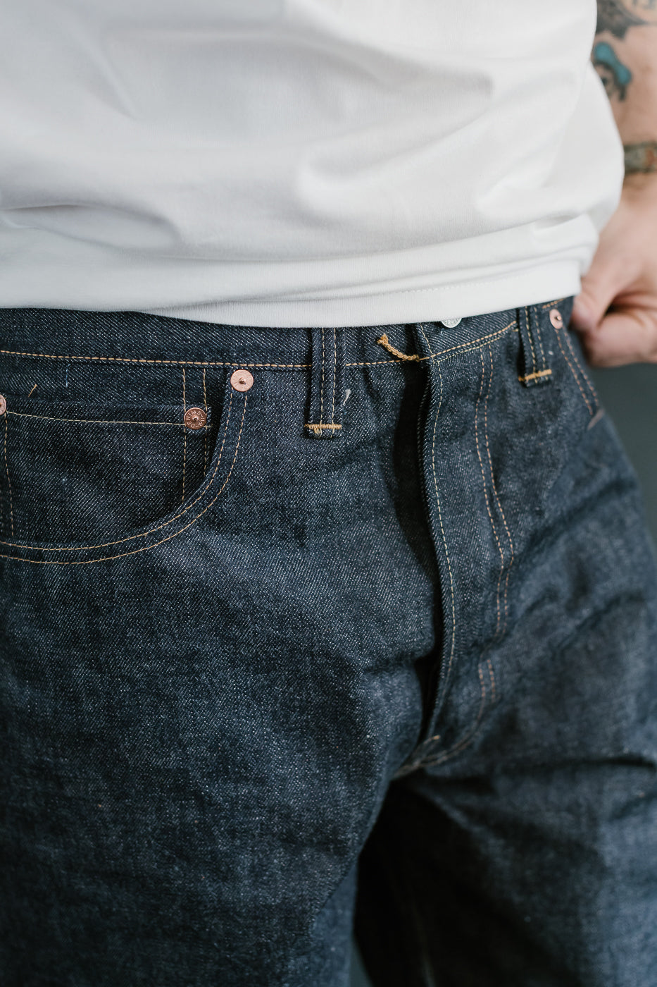 Close-up of a person wearing dark blue jeans with a blurred background