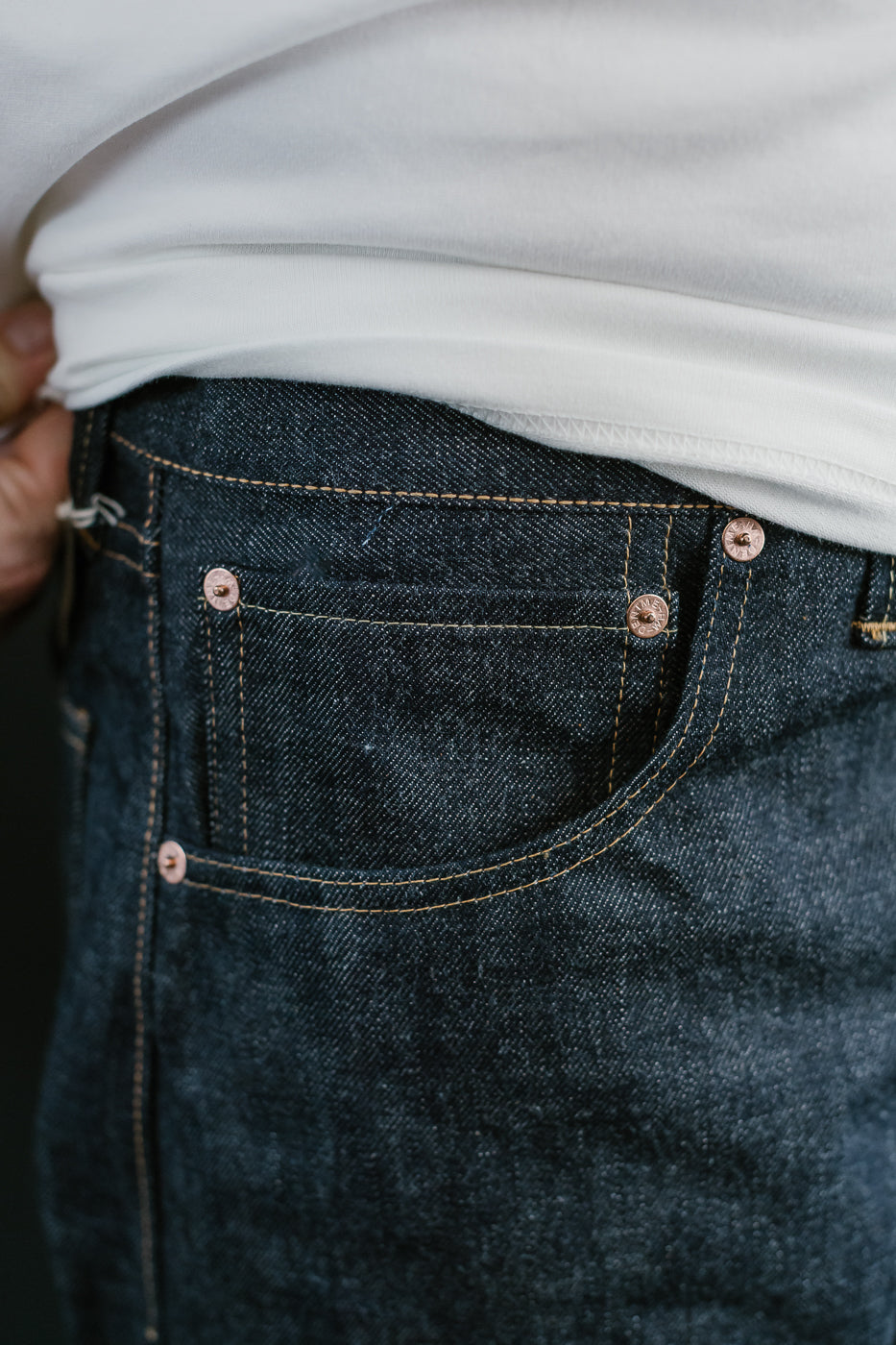 Close-up of dark blue jeans with a white shirt underneath