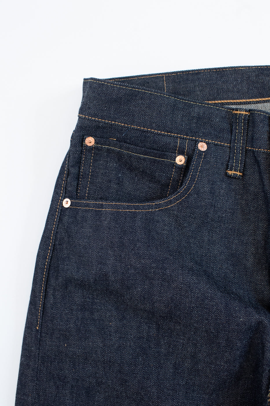 Close-up of dark blue denim jeans on a white background